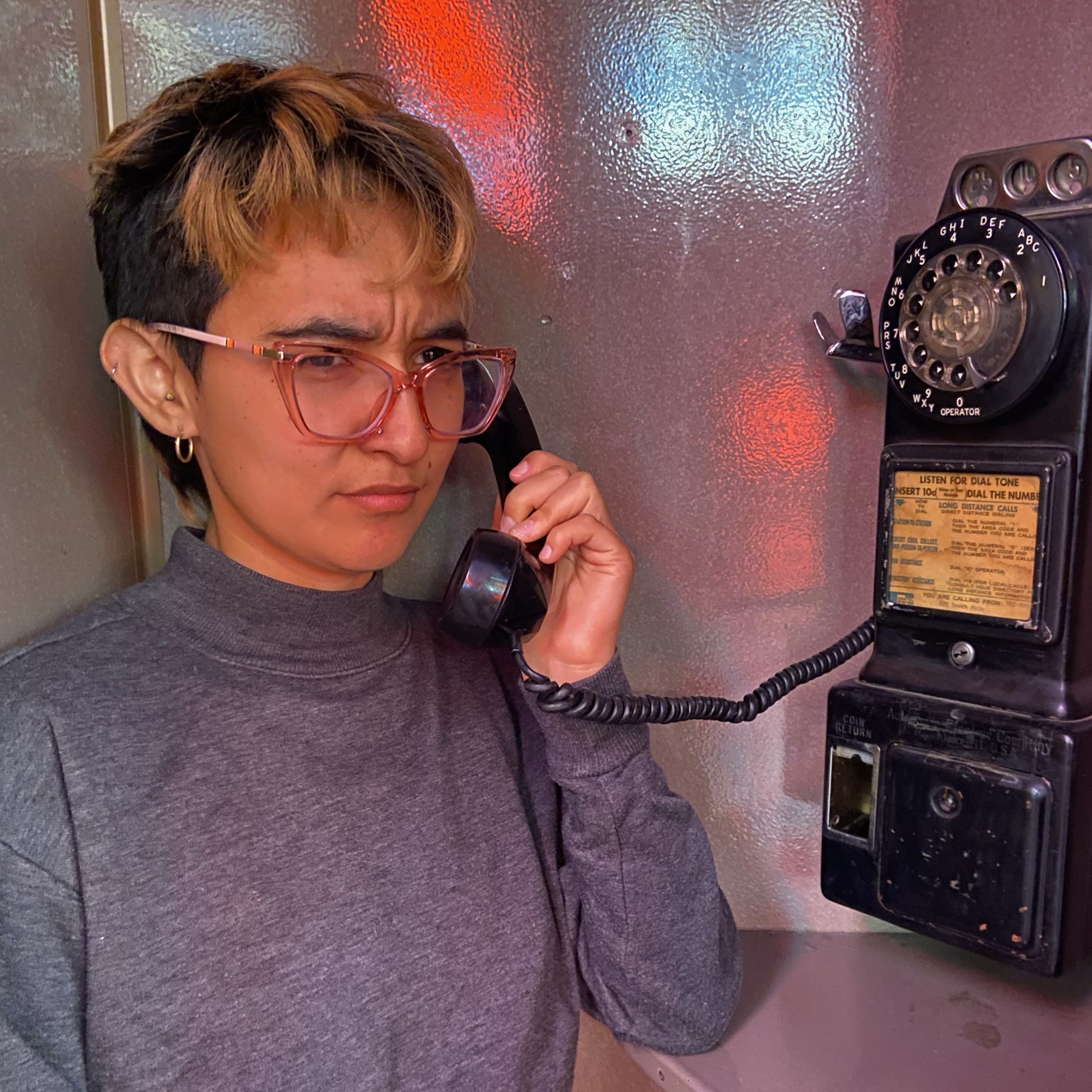 a headshot of leo answering a phone in a callbox